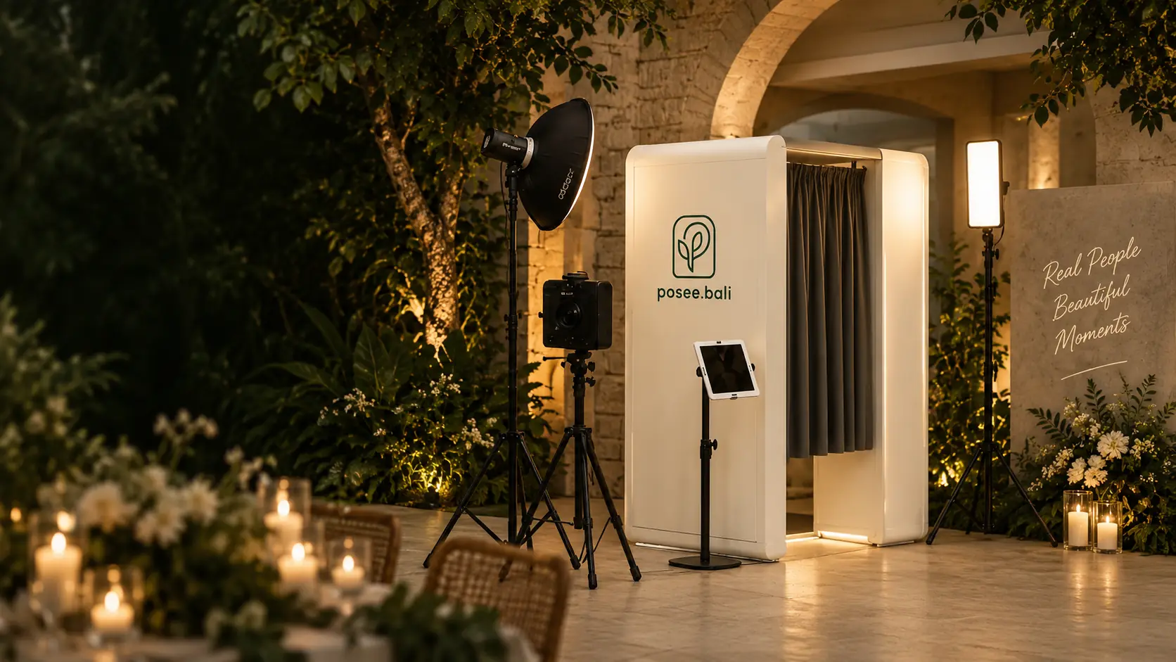 A white posee.bali photobooth lit warmly at an evening garden event in Bali